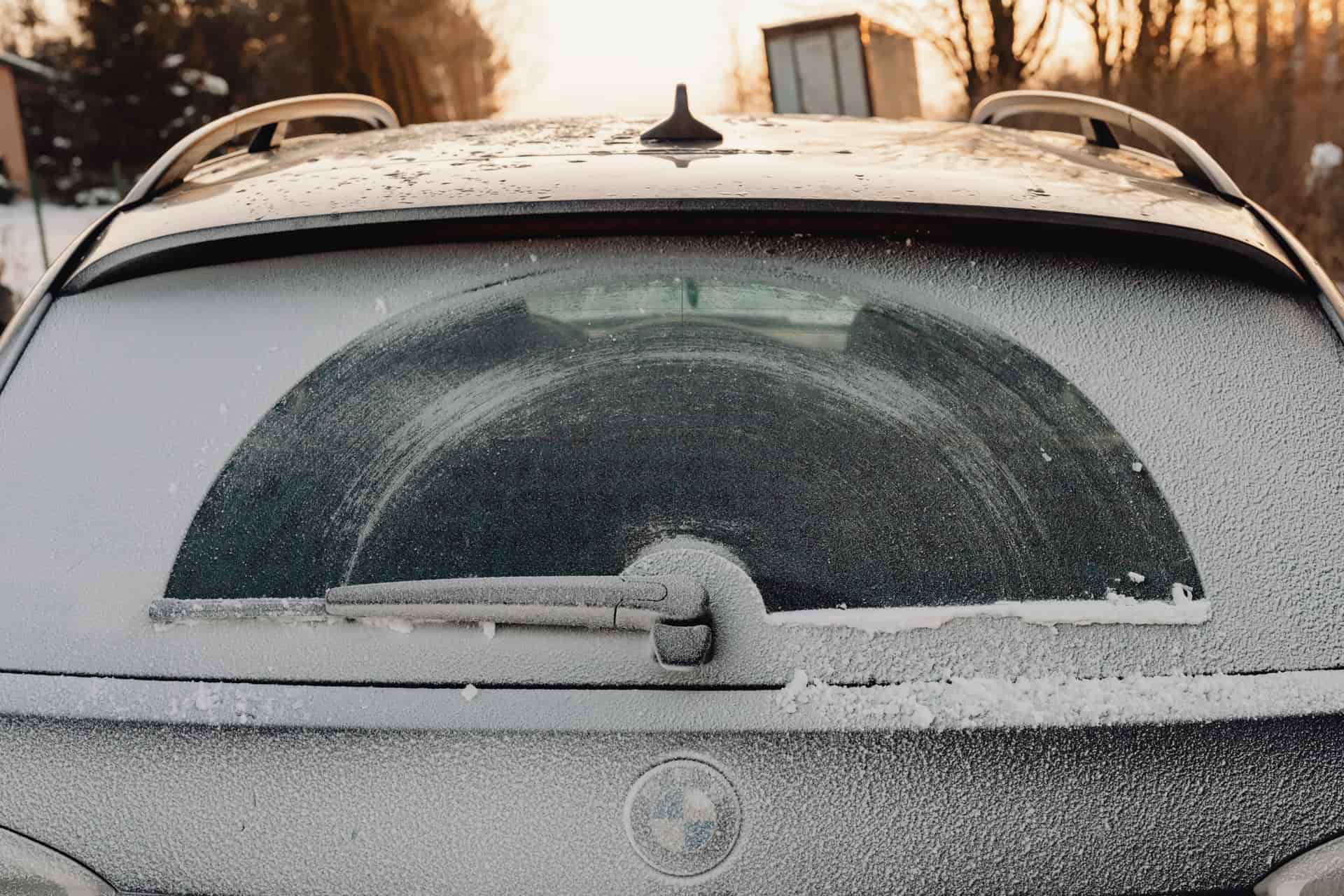 A car windshield covered in a thick layer of ice on a winter morning